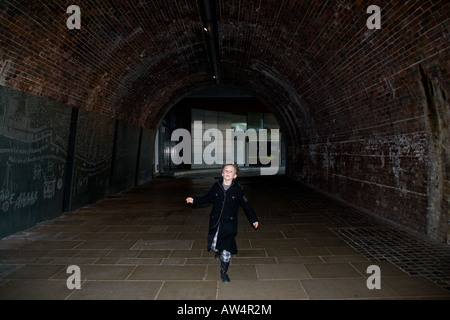 young boy running through dark tunnel in london Stock Photo