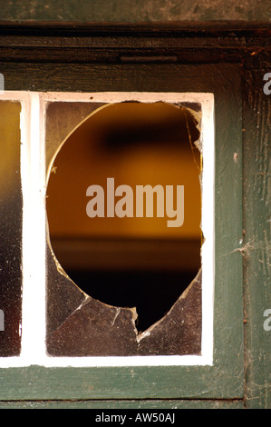 a broken window in an old building having been derelict smashed deserted and vandalised by criminals breaking in and the glass Stock Photo