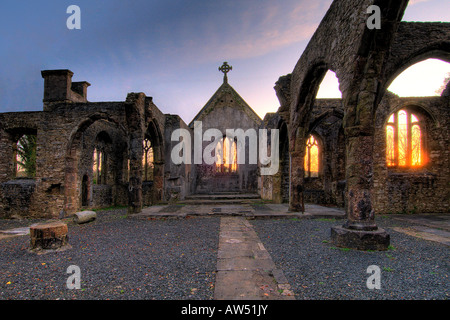 Interior of a burnt out church attacked by arsonists and left as a ruin with a blazing sunrise through the glassless windows Stock Photo