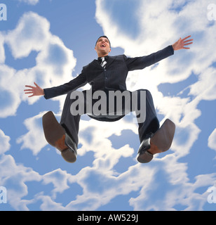 Young smiling businessman flying in the air he is looking at something Low angle view Stock Photo