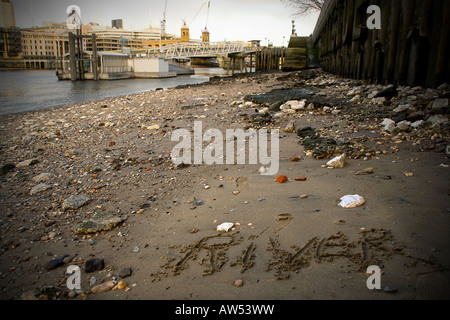 unusual view of thames foreshore with 'river' written in sand, with st pauls and millennium bridge in the background Stock Photo