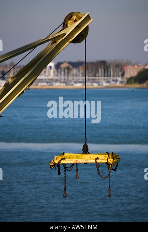 yellow lifting machinery against blue water Stock Photo