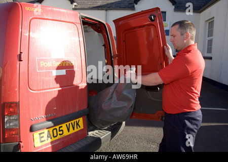 Postman post man working Red tee shirt. GPO. Horizontal Narberth Post Office Red van car post bag facing Horizontal sunny Stock Photo