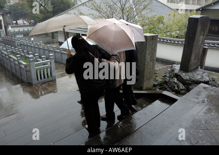 People under umbrellas, Sengaku-ji temple, Tokyo Stock Photo