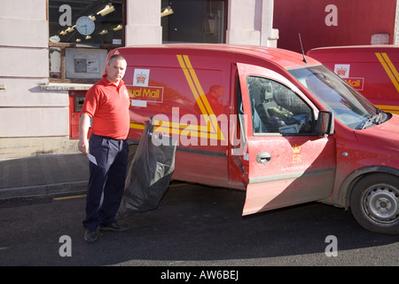 Postman post man working Red tee shirt. GPO. Horizontal Narberth Post Office Red van car post bag facing Horizontal sunny Stock Photo