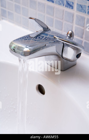 DUAL TAP RUNNING WATER IN SINK IN BATHROOM UK Stock Photo