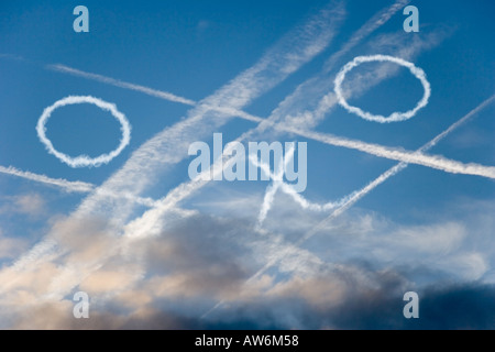 CROSSED CONTRAILS IN BLUE SKY WITH NOUGHTS AND CROSSES Stock Photo