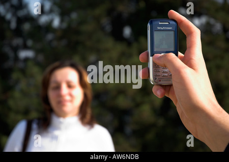 Male hand holding camera phone taking picture of young woman Stock Photo