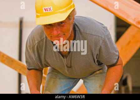 Construction worker looking up and smiling - wearing a yellow hard hat Stock Photo
