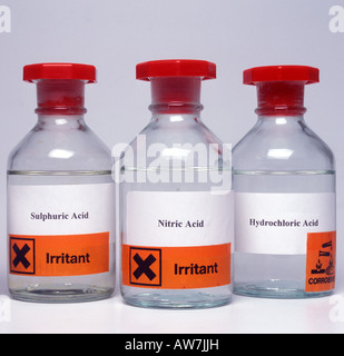 Bottles of laboratory acids with hazard labels Stock Photo