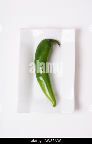 Green hot spicy Chili on a white plate Stock Photo