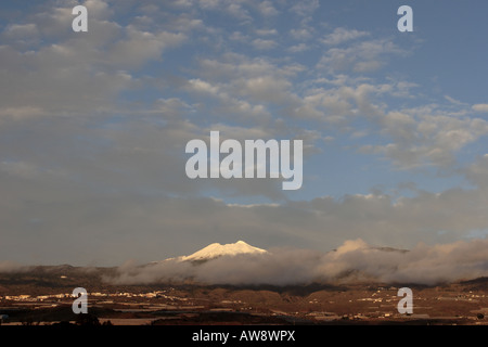 Mount Teide covered in snow above the clouds late in the day Stock Photo