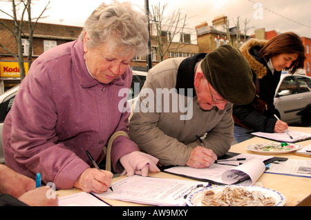Members of the public signing a petition against possible closure of their local Post Office High Street New Malden Surrey UK Stock Photo
