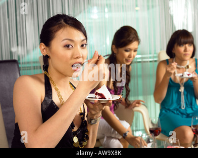 lady eating cake with friends at a party Stock Photo
