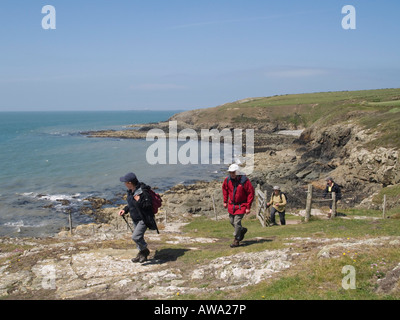 Group of people walking on Anglesey Coastal Path during Walking Festival in summer Church Bay Anglesey North Wales UK Stock Photo