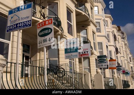 A row of Estate agents For Sale Sold Sale Agreed To Let and Let boards festoon a terrace of sea view houses on Hastings seafront Stock Photo