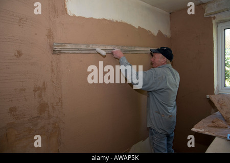 levelling first coat of plaster on wall Stock Photo