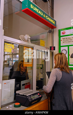 Woman customer using Bureau de Change facility at her local post office, High Street, New Malden, Surrey, UK. Stock Photo