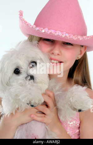 Girl wearing a cowboy hat holding a dog” Stock Photo