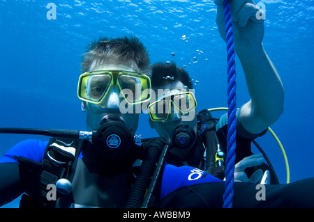 Alexander Caminada and Chris Sly. Two male scuba divers doing decompression stop holding on to shot line. Stock Photo