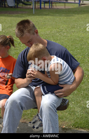 Pre-K male with a bloody knee is consoled by his Father Stock Photo