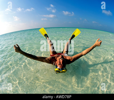 Young man wearing flippers laying in shallow water, vacation, Maldives, Indian Ocean Stock Photo