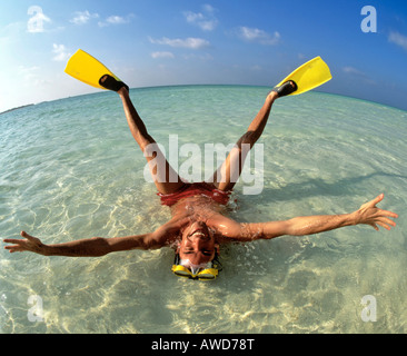 Young man wearing flippers laying in shallow water, vacation, Maldives, Indian Ocean Stock Photo