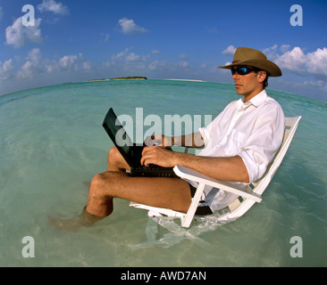Young man with laptop sitting on deck chair, work and relaxation, vacation and stress, Maldives, Indian Ocean Stock Photo
