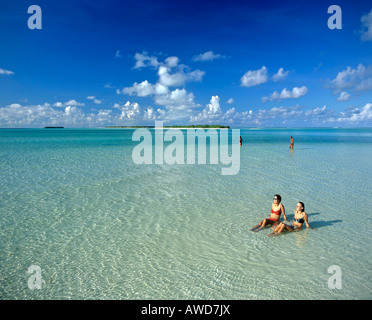 Young women relaxing in shallow water, island at the back, Maldives, Indian Ocean Stock Photo