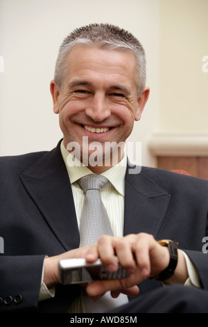 Smiling buisnessman holding mobile phone Stock Photo