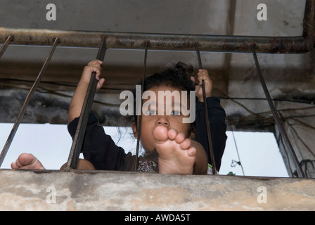 Girl at the bannister in the staircase of an appartment block, Dey Krahom slum area, Phnom Phen, Cambodia Stock Photo