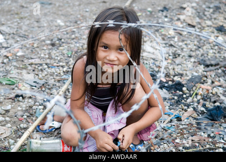 Girl playing between barbed wire in a slum. The inhabitants are being threatened by forced resettlement, Dey Krahom slum area,  Stock Photo