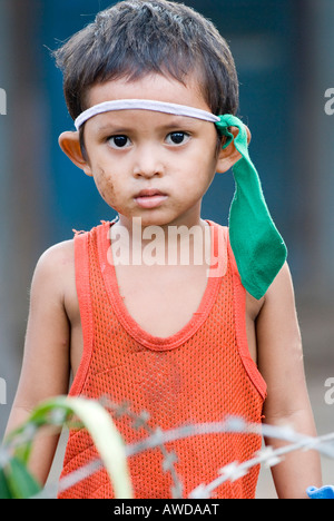 Boy dressed as indian playing between barbed wire in a slum. The inhabitants are being threatened by forced resettlement, Dey K Stock Photo