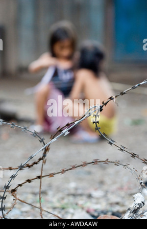 Children playing behind barbed wire in a slum. The inhabitants are being threatened by forced resettlement, Dey Krahom slum are Stock Photo