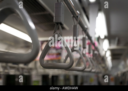 Handles hang from the roof of Tokyo subway train. Narrow depth of field provides selective focus on one handle. Stock Photo