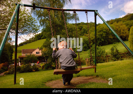 A YOUNG BOY PLAYS ON A SWING AT THE NEW INN IN WATERLEY BOTTOM NEAR DURSLEY GLOUCESTERSHIRE UK Stock Photo
