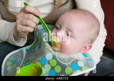 A five month old baby boy tries solid food for the first time Stock Photo