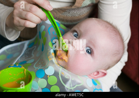 A ffive month old baby boy tries solid food for the first time Stock Photo