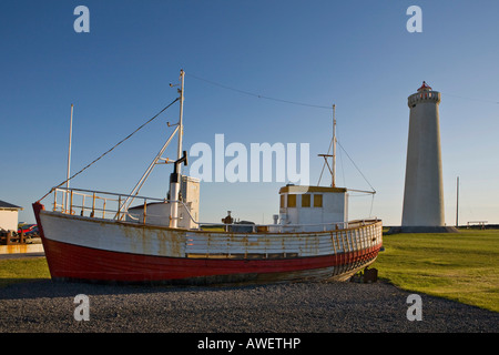 Old fishing cutter in front of Garðskagi Lighthouse, tallest in Iceland, Garður, Iceland, Atlantic Ocean Stock Photo