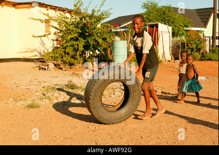 Boy playing on dirt road with an old tire, Sehitwa, Botswana, Africa Stock Photo