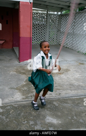 Girl wearing school uniform playing with a skipping rope at an Ursuline convent and orphanage in Georgetown, Guyana, South Amer Stock Photo