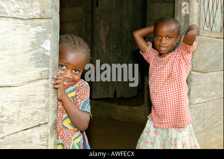 Children standing in the front door to their house, Cameroon, Africa Stock Photo