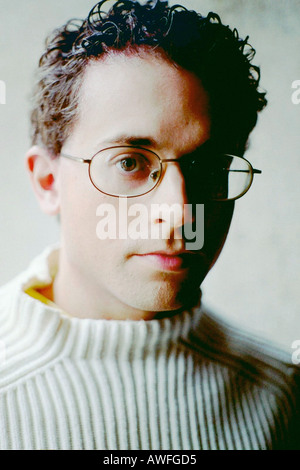Portrait of a Young Man in a White Sweater He Has Curly Hair and is Wearing Eyeglasses Stock Photo