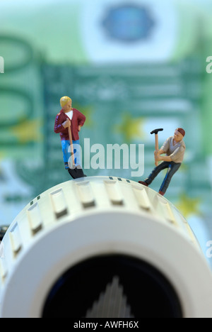 Two workers with pick and shovel on a thermostat, 100 Euro bill in the background Stock Photo