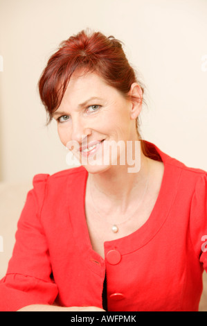 Middle-aged woman wearing red top, smiling Stock Photo