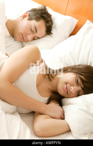 Young couple sleeping in bed, smiling Stock Photo