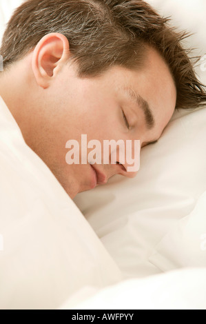 Young man lying in bed, sleeping Stock Photo