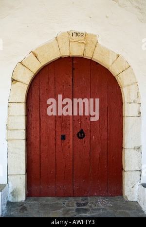 large old red wooden door in small chapel adjacent to the cemetery of Port Lligat in Spain Stock Photo