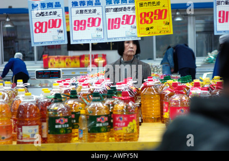 Chinese lady looks at the sale price tags of bottle cooking oil in a supermarket in Beijing, China. 12 Mar 2008 Stock Photo