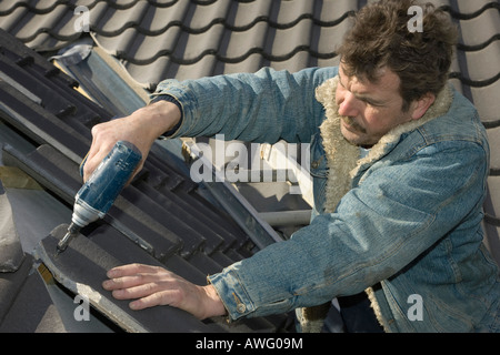 a builder fitting tiles to a roof of a new home Stock Photo